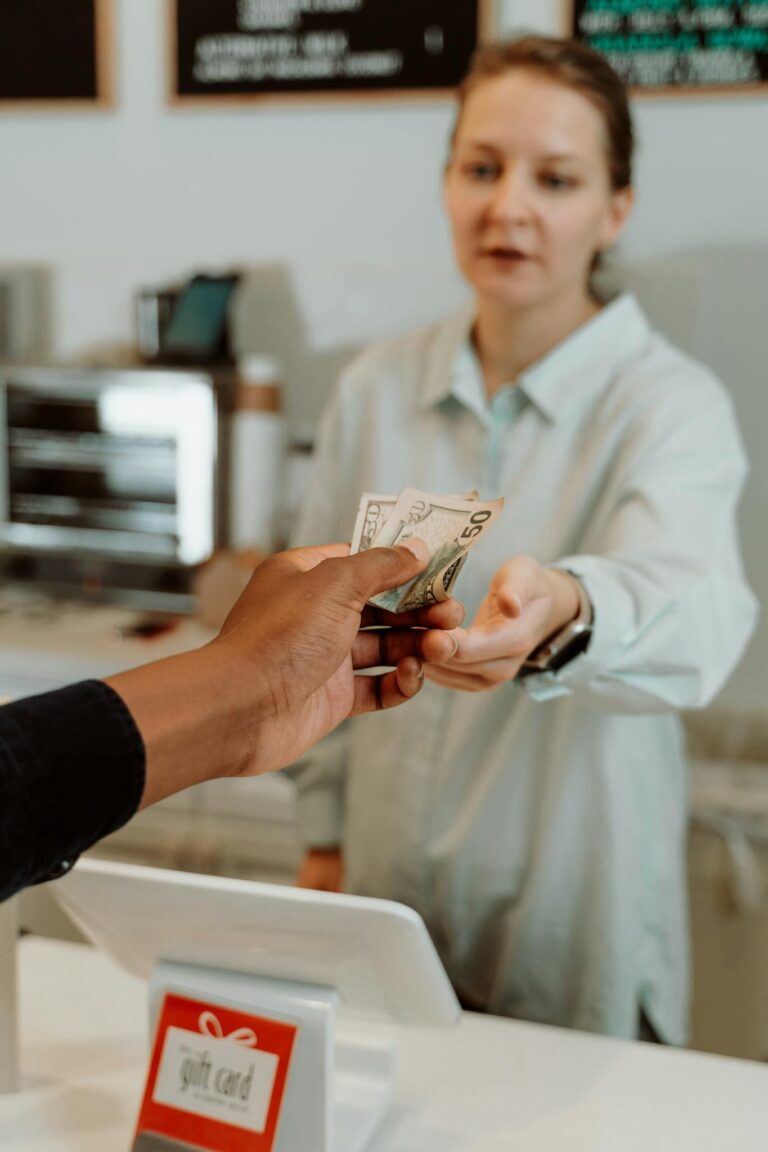 A female cashier receiving cash payment from a customer at a retail store.